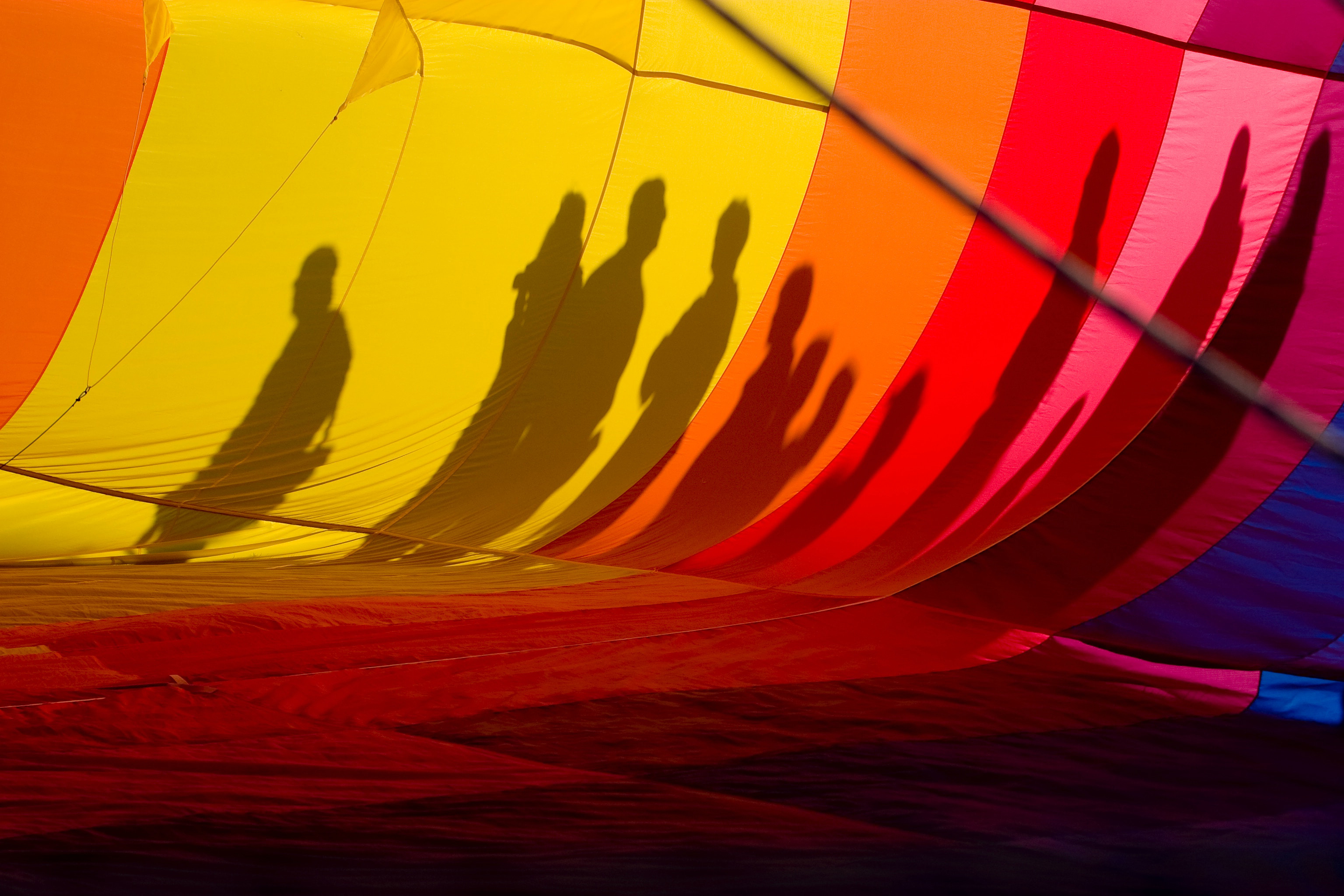 Rainbow coloured hot air balloon with shadows of people.